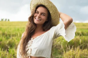 Femme avec un chapeau de paille, elle est dans un champ au soleil