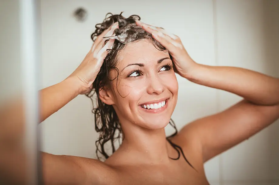 Femme qui se lave les cheveux et sourit face à la caméra